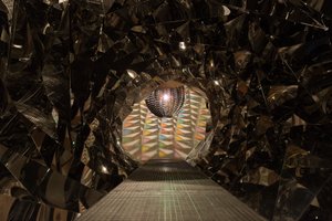 Looking down a metallic tunnel to a light fixture at the end.