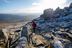 Chris descends a gently sloping hillside covered in large frost-covered boulders.